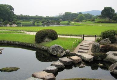 延養亭からの眺める池と緑の芝生が広がった庭園内の写真